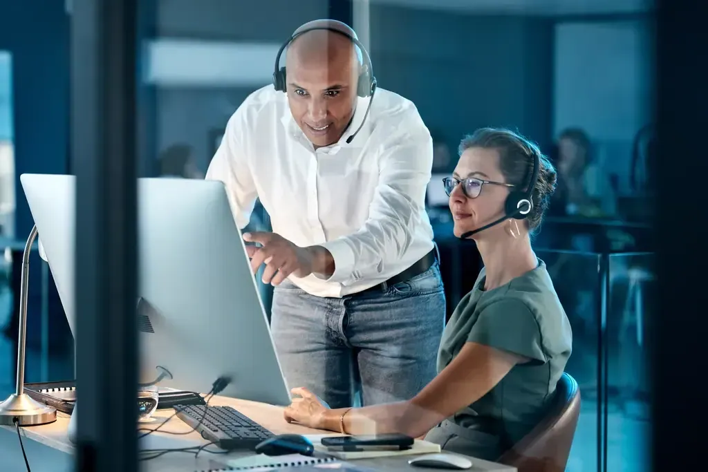 Manager helping his coworker in front of a monitor
