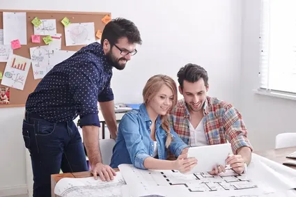 Group of young creative architects looking at a tablet