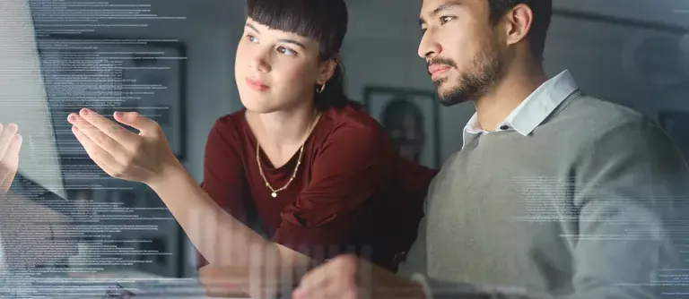 A young woman helping a male employee with a computer in front of them