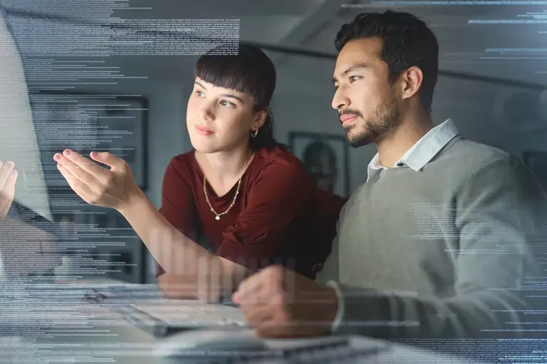 A young woman helping a male employee with a computer in front of them