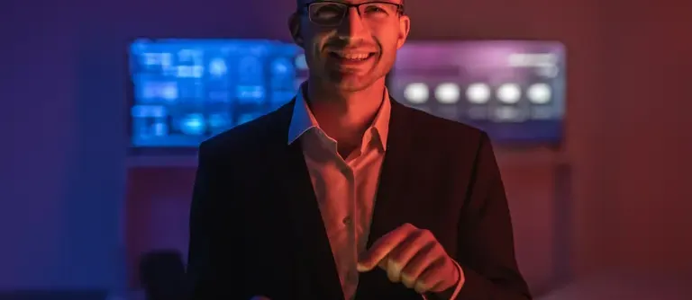 Happy man with glasses working with a tablet in a dark room