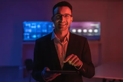 Happy man with glasses working with a tablet in a dark room