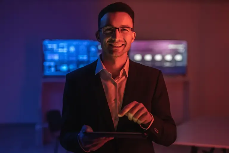Happy man with glasses working with a tablet in a dark room